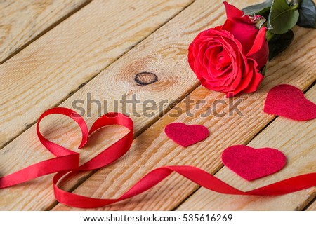 Red  hearts with red ribbon  and a rose lie on wooden table  with free text space