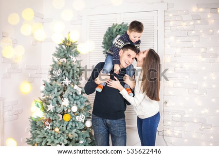 Family of mother, father and little child near Christmas tree with presents, decorations and New Year or Christmas
