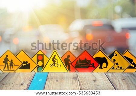 Set of traffic warning sign on blur traffic road with colorful bokeh light and old empty wood table background.Copy space of transportation and travel concept. Product display presentation.Retro tone.