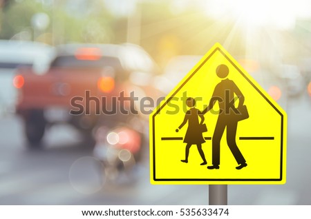 School zone warning sign on blur traffic road with colorful bokeh light abstract background. Copy space of transportation and travel concept. Vintage tone filter color style. 