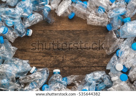 Recycling concept. Ecology problem, environmental pollution. Frame background of plastic bottles with wooden texture. In the center is an empty place for text. Royalty-Free Stock Photo #535644382
