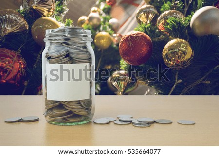 money in the glass bottle with decorated Christmas tree background blur
