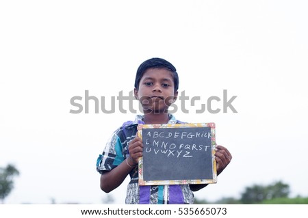 Rural School boy holding slate with English alphabet