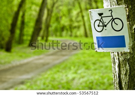 Bike sign with bicycle path in background. Park.