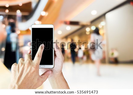 Girl use mobile phone, blur image of family walk in the mall as background.