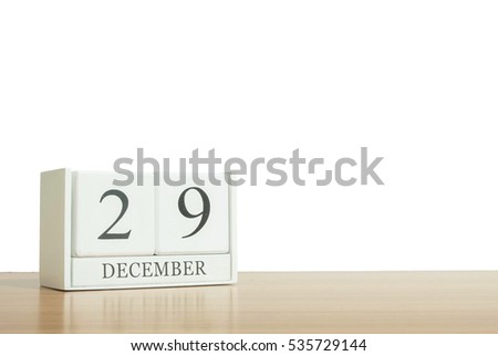Closeup surface white wooden calendar with black 29 december word on blurred brown wood desk isolated on white background with copy space , selective focus at the calendar