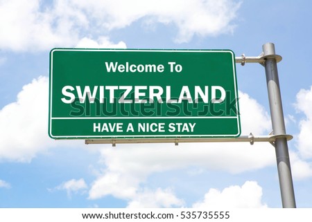 Green overhead road sign with a Welcome to Switzerland, Have a Nice Stay concept against a partly cloudy sky background.