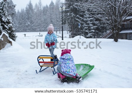 children sledding and snow play in the street near  the house Royalty-Free Stock Photo #535741171