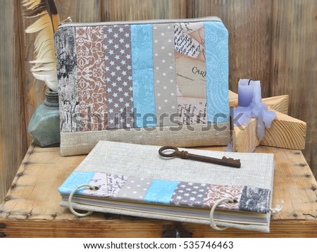 Set the writer for creativity and handmade: a notebook turquoise craft patchwork, textile pencil case, vintage feather and ink, rusty key, star candle holder on a brown wooden rustic background. 