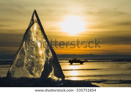 A motor vehicle on the Baikal lake in winter during sunset