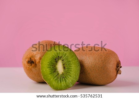 Fresh juicy sliced kiwi fruit on a table isolated on pink background