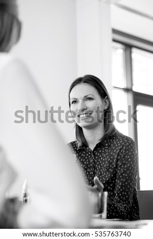 Confident young businesswoman talking with female colleague in meeting room