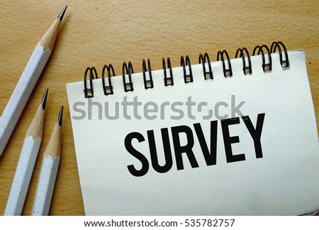 Survey text written on a notebook with pencils