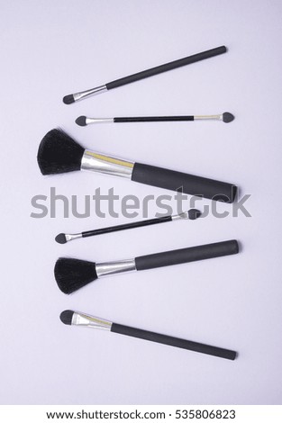 Aerial view of cosmetic make up brushes on a pastel purple background