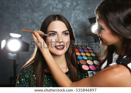 Professional makeup artist working with beautiful young woman Royalty-Free Stock Photo #535846897