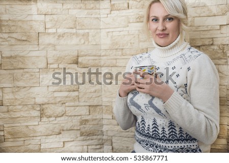 Portrait of a young woman in a white sweater close-up of a cup of coffee