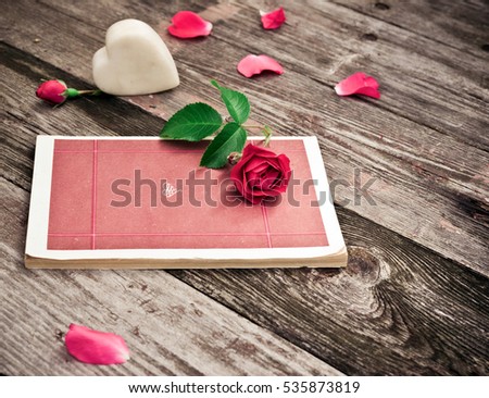 Flowers. Red roses with Book, Heart and Petals on wooden table. Vintage Valentine Floral background. Toned image in retro style.