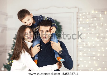 Family of mother, father and little child near Christmas tree with presents, decorations and New Year or Christmas