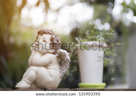 Angel or cupid figure with the green background with sun lighting