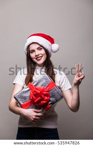 Christmas Woman with Gift Box. Beautiful Brunette Girl in Santa Hat isolated.