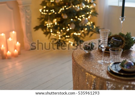Interior dining room with a fireplace, a Christmas tree with colour lights and a festive table with dishes