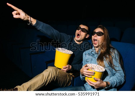 Cinema day, young couple with popcorn looking horror movie in cinema.