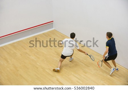 Squash players in action on squash court, back view/Two men playing match of squash. Royalty-Free Stock Photo #536002840