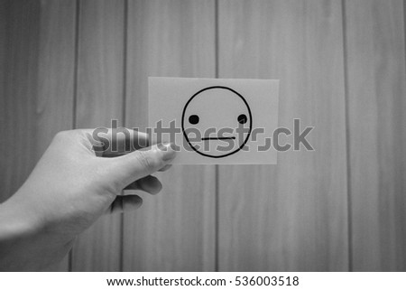 grayscale hand holding stunning face card on wooden background