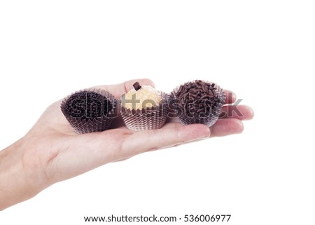 Girl's hand holding some traditional candies from Brazil called brigadeiro.