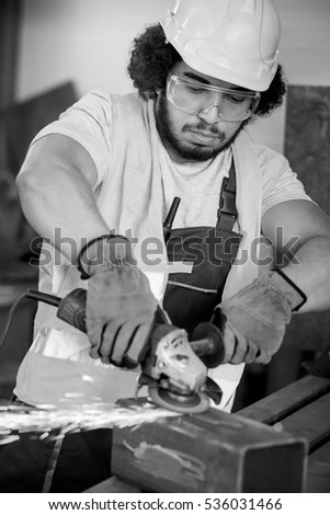 Young manual worker grinding metal in industry