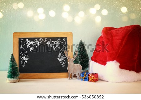 Image of christmas trees and santa hat next to blackboard

