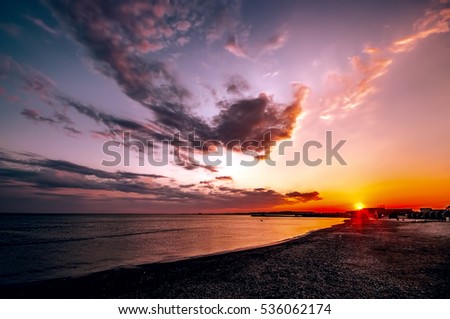 Beautiful blazing sunset landscape at Caspian sea and orange sky above it with awesome sun golden reflection on calm waves as a background. Amazing summer sunset view on the beach. Azerbaijan, Baku