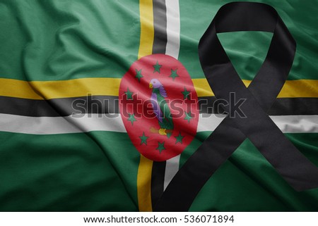 waving national flag of dominica with black mourning ribbon
