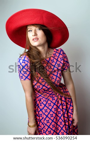 Fashion Brunette Lady in red hat and red blue dress on white grey background. studio shot vertical image picture