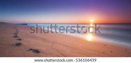 Footsteps in the sand during a sunrise panorama Royalty-Free Stock Photo #536106439