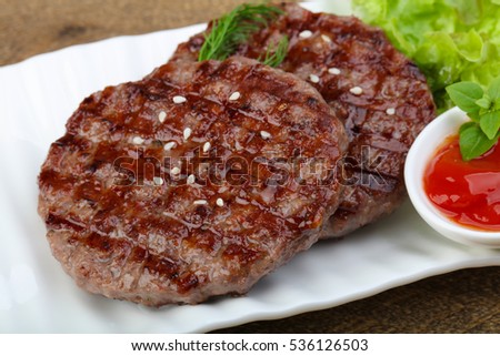 Grilled burger cutlet with onion and salad leaves