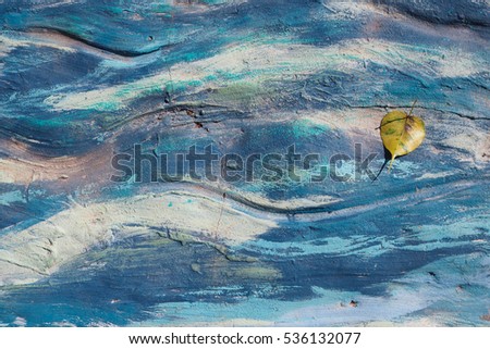 Yellow leaf in front of different shade of blue wave
