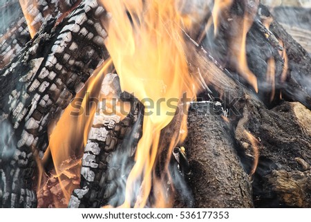 wooden logs burning generating orange flames and white smoke in a stove placed in the street in the Austrian town of Villach in Christmas time