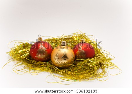 Christmas balls with a picture of two red and one gold on gold tinsel isolated on white background