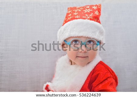 very cute baby wearing glasses in a suit of Santa Claus
