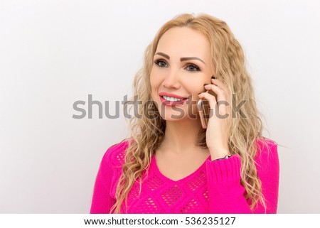 Smiling blonde woman talking on the phone over white background. A portrait of a beautiful blonde woman