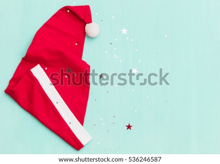 Top view on Santa's hats on retro wooden turquoise background with shiny stars. Christmas, winter and holidays season concept.