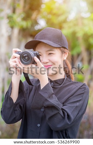 Young beautiful woman in hat is taking picture with old fashioned camera,