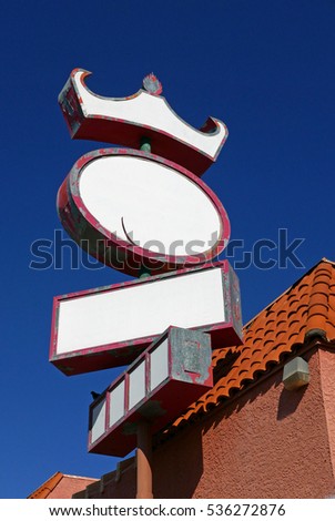 Blank oval white sign on the side of a tiled roof with a crown-like addition against blue sky