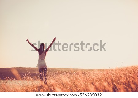 Free woman raising arms to golden sunset. Freedom and success concept. Girl relaxing and enjoying nature with copy space. Toned film effect Royalty-Free Stock Photo #536285032