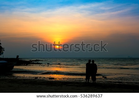 silhouette man and woman on the beach at sunset over sea background