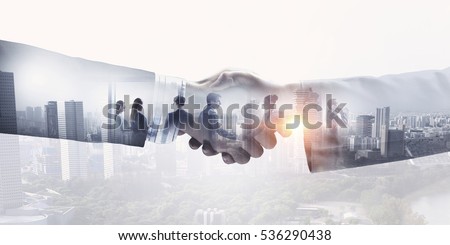 Partners shaking hands . Mixed media Royalty-Free Stock Photo #536290438