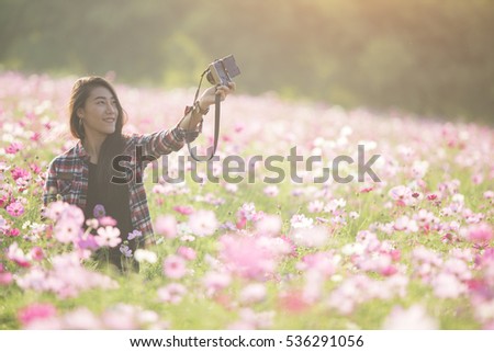 Pretty young female tourist takes travel selfie at the cosmos flower field. The concept of relax.Soft focus.