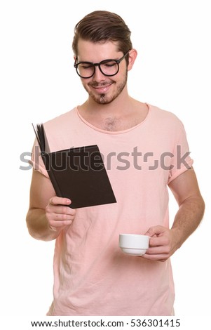 Young happy Caucasian man reading book while holding coffee cup