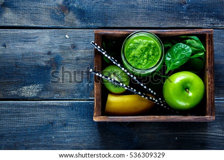 Green fresh smoothie in jar with fruit, greens and vegetables in old wooden box, dark background, top view. Detox, dieting, clean eating, vegetarian, vegan, fitness, healthy lifestyle concept